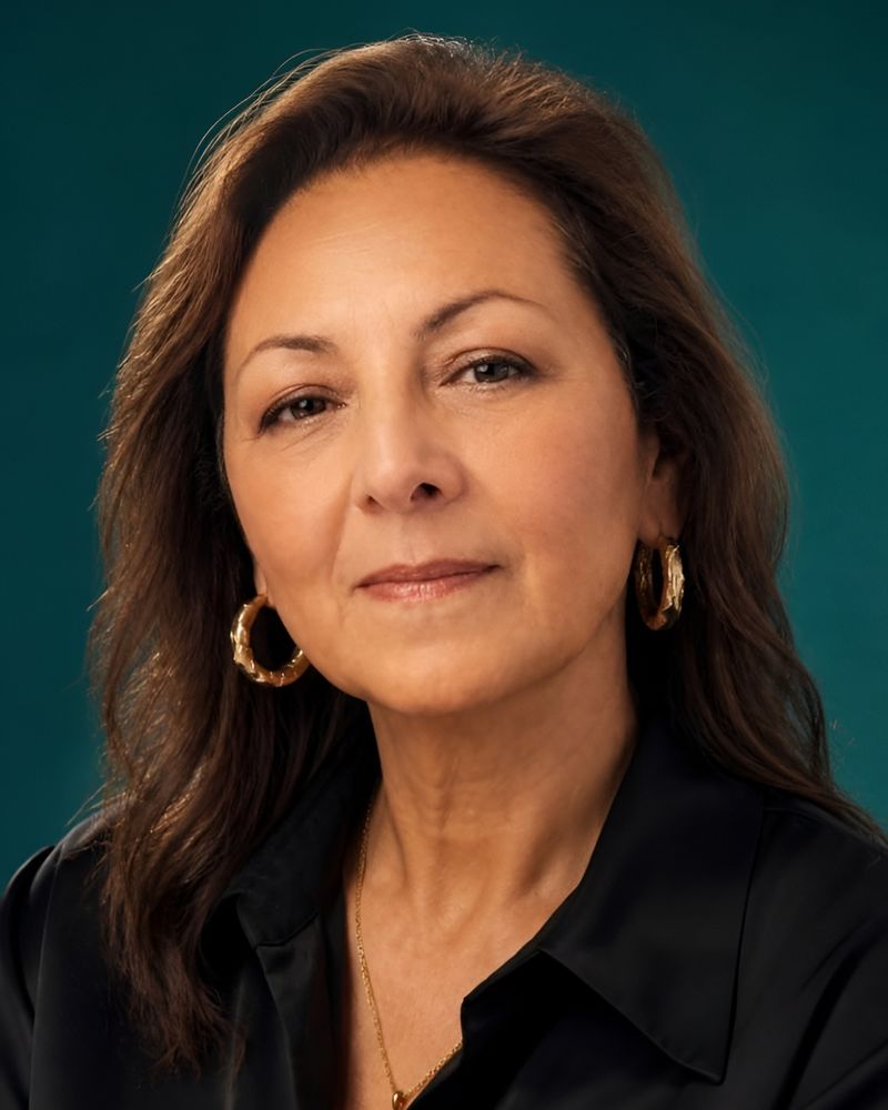 Retrato de Rosalba Muñoz Londoño, Administradora de Empresas: mujer de pelo castaño, con aros dorados y camisa negra, sonriendo ligeramente a cámara.
